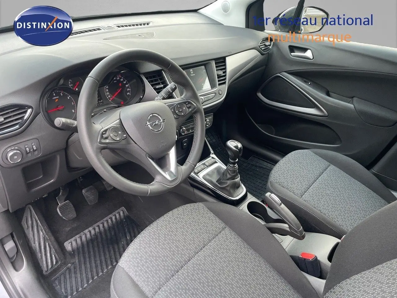 Vue intérieure côté conducteur de l'Opel Crossland 2022 avec tableau de bord noir et sièges tissu gris.