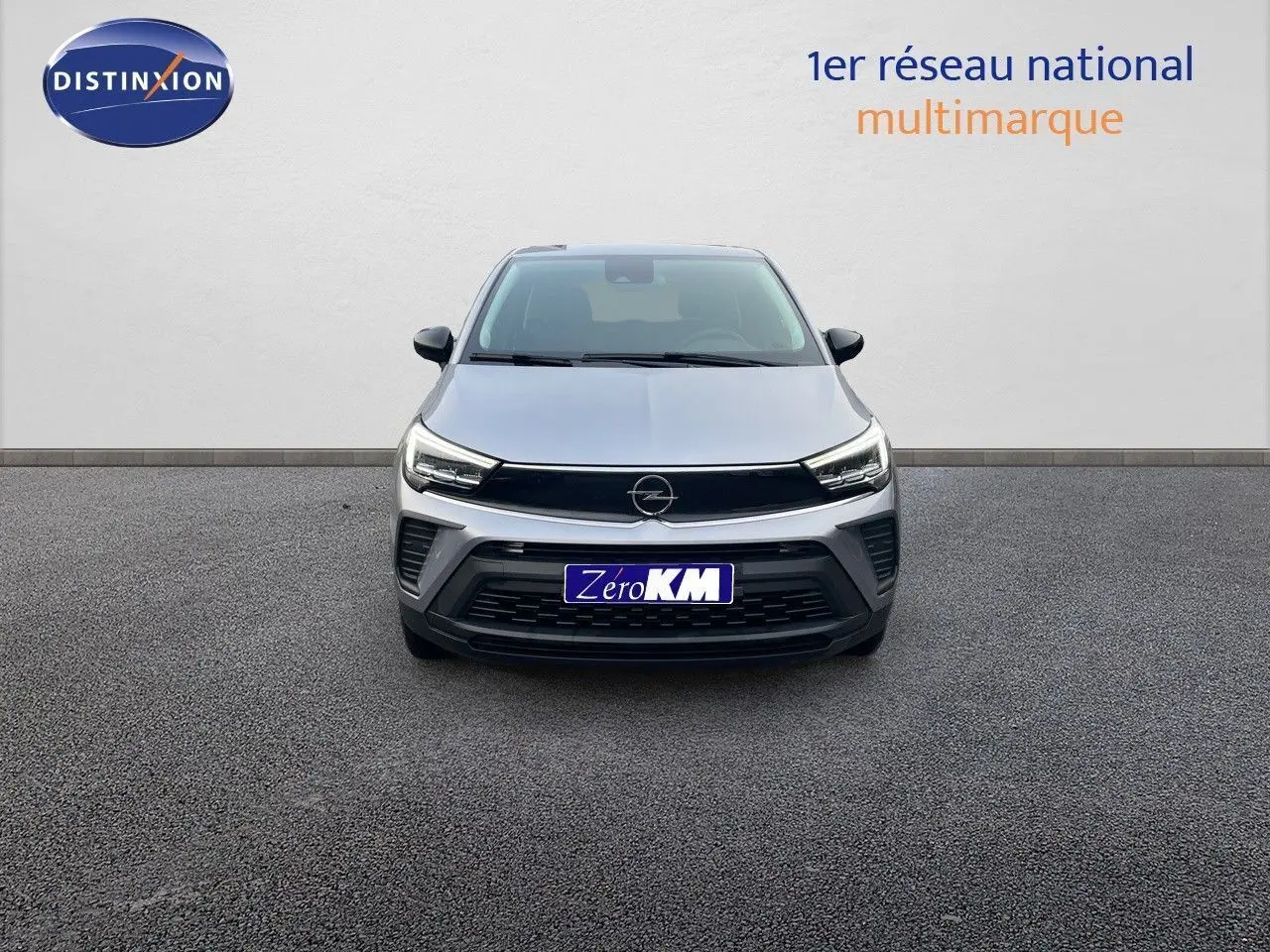 Vue frontale d'un Opel Crossland gris minéral métal avec calandre noire et phares LED allumés sur fond neutre.
