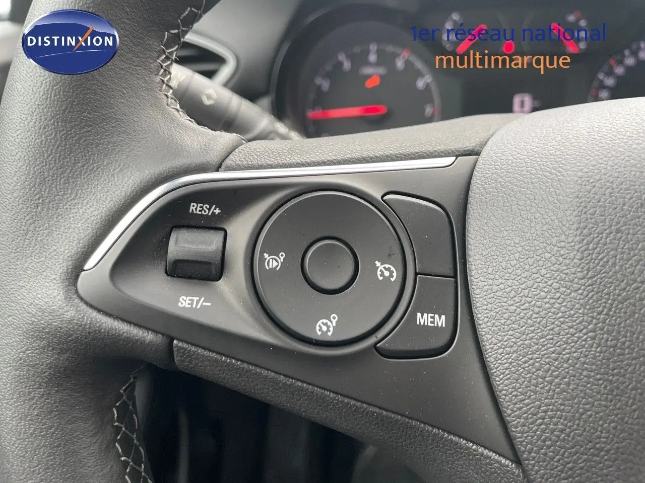 Gros plan sur les commandes au volant du Opel Crossland gris minéral 2022, avec tableau de bord flou en arrière-plan.