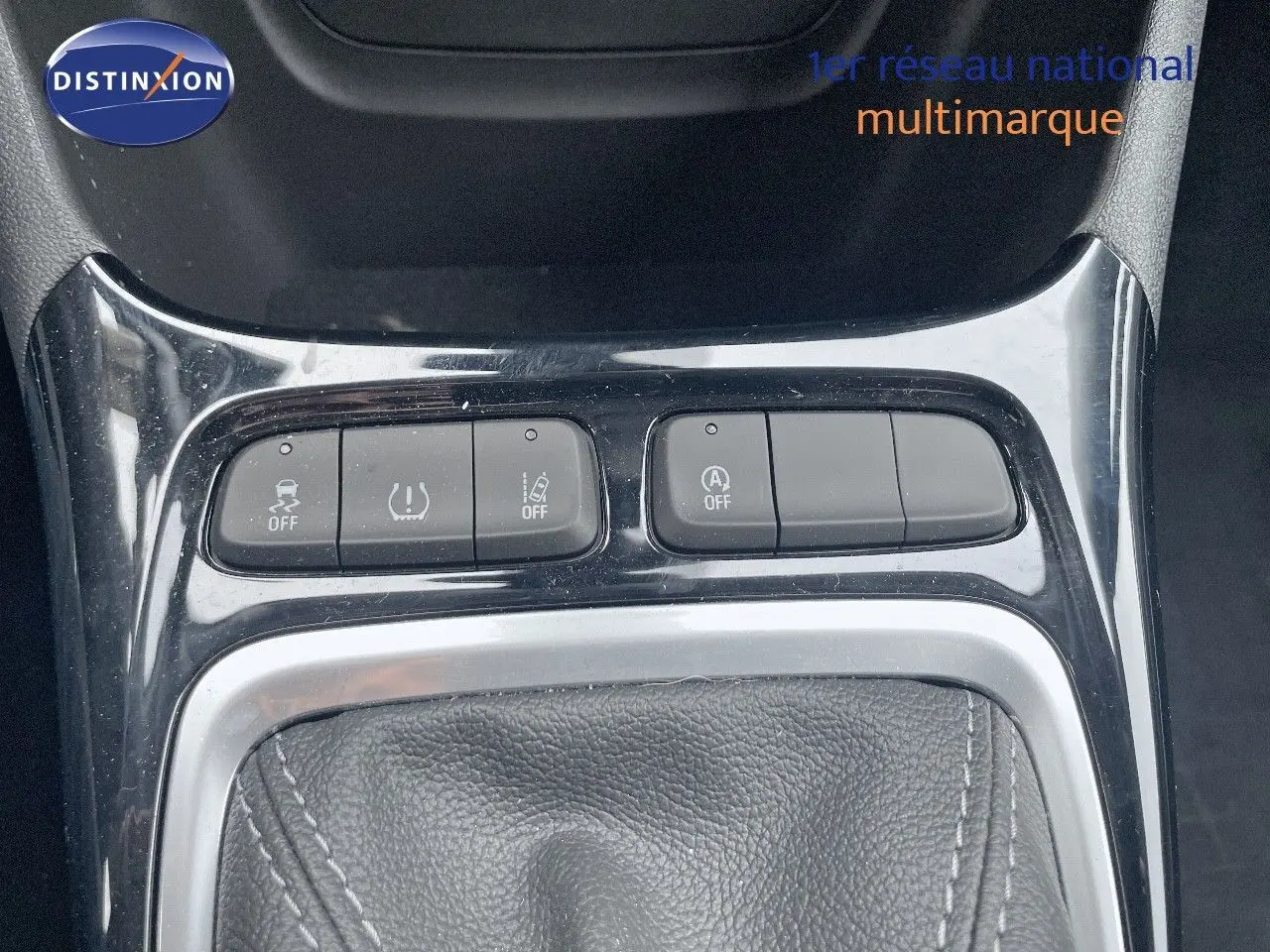 Gros plan sur la console centrale de l'Opel Crossland gris minéral, montrant les boutons de contrôle et le soufflet de levier de vitesses.