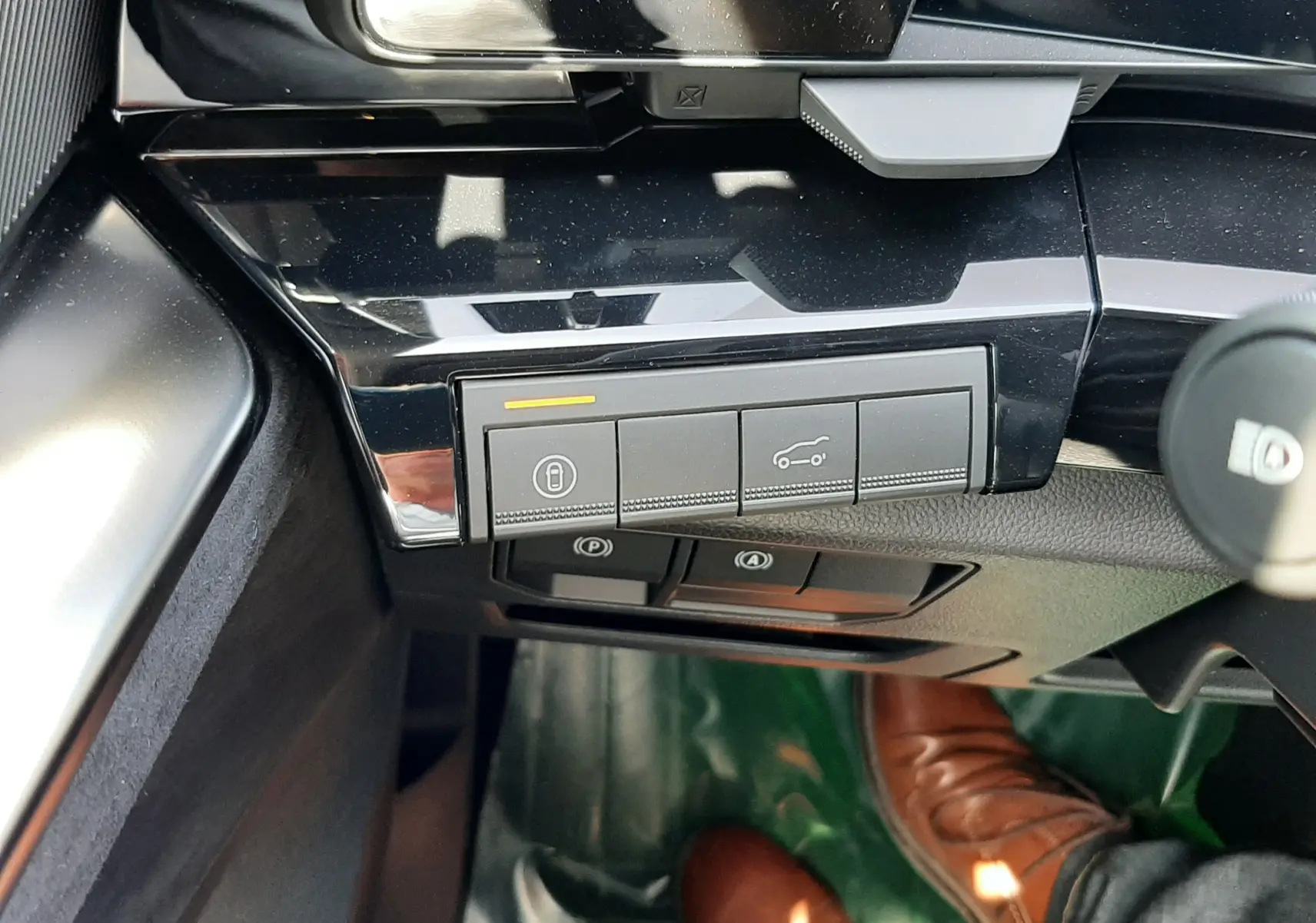 Gros plan sur les commandes noires du tableau de bord du Renault Espace gris, avec pédales et chaussure brune visibles au sol.