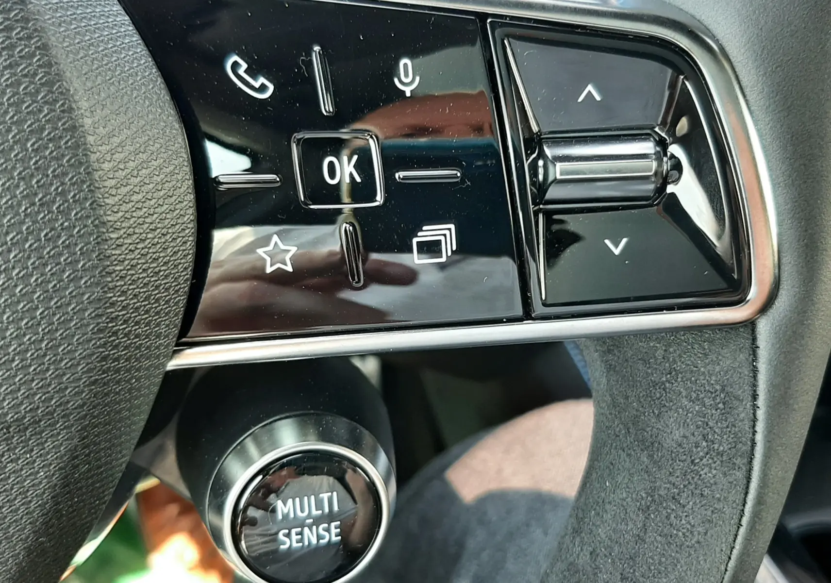 Gros plan sur les commandes gauche du volant en cuir noir et alcantara du Renault Espace VI gris schiste, avec bouton Multi Sense.