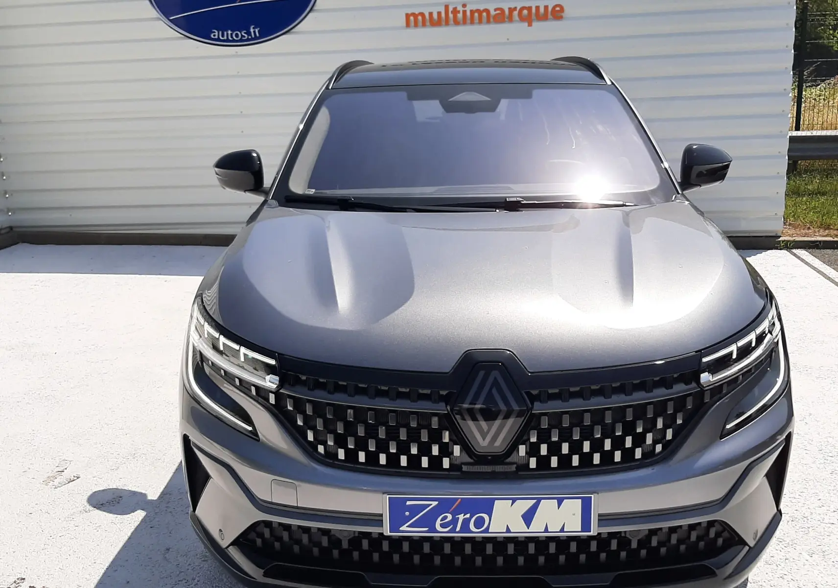 Vue avant d'un Renault Espace VI gris schiste métal, avec calandre à damier et logo central proéminent.