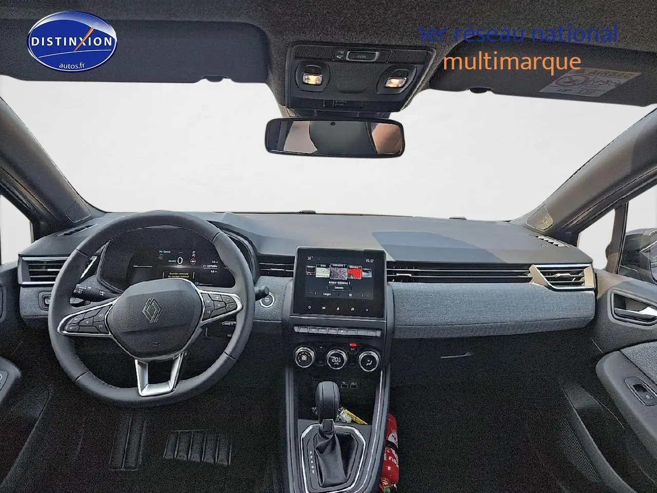 Vue intérieure avant de la Renault Clio V gris schiste, tableau de bord moderne avec écran tactile central et volant multifonction.