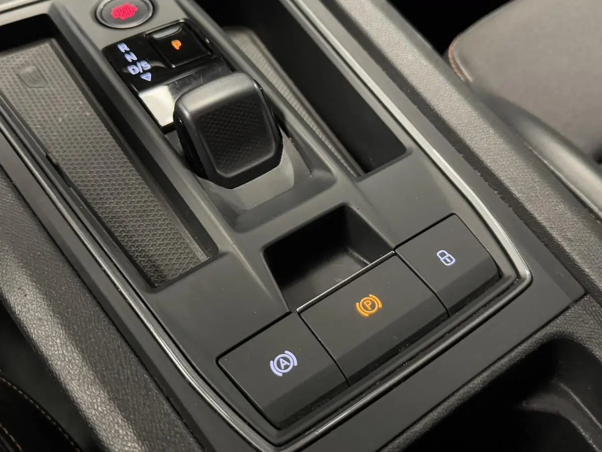 Gros plan sur la console centrale noire de la CUPRA Leon Sportstourer 1.4 e-Hybrid avec levier de vitesse et boutons éclairés.