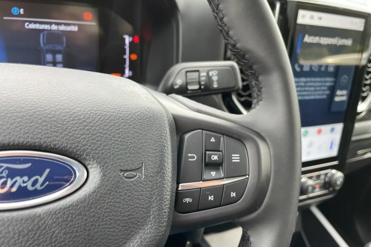 Gros plan sur le volant cuir multifonctions du Ford Ranger gris carbone avec écran tactile et commandes au volant visibles.
