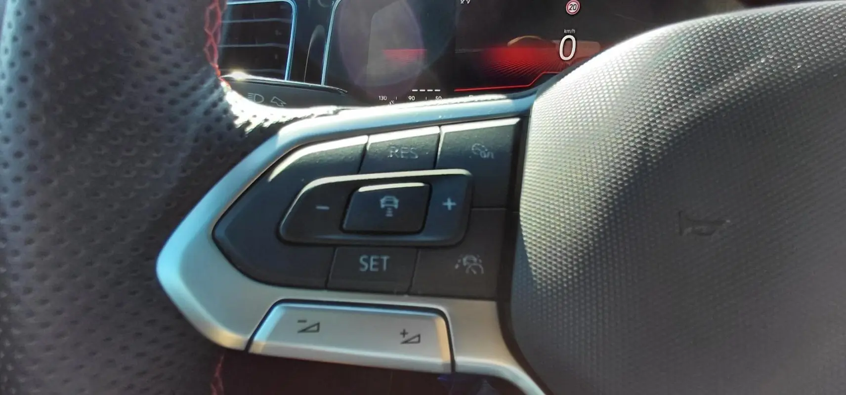 Gros plan sur les commandes du volant sport noir de la Volkswagen Polo GTI 2024 avec affichage numérique en arrière-plan.