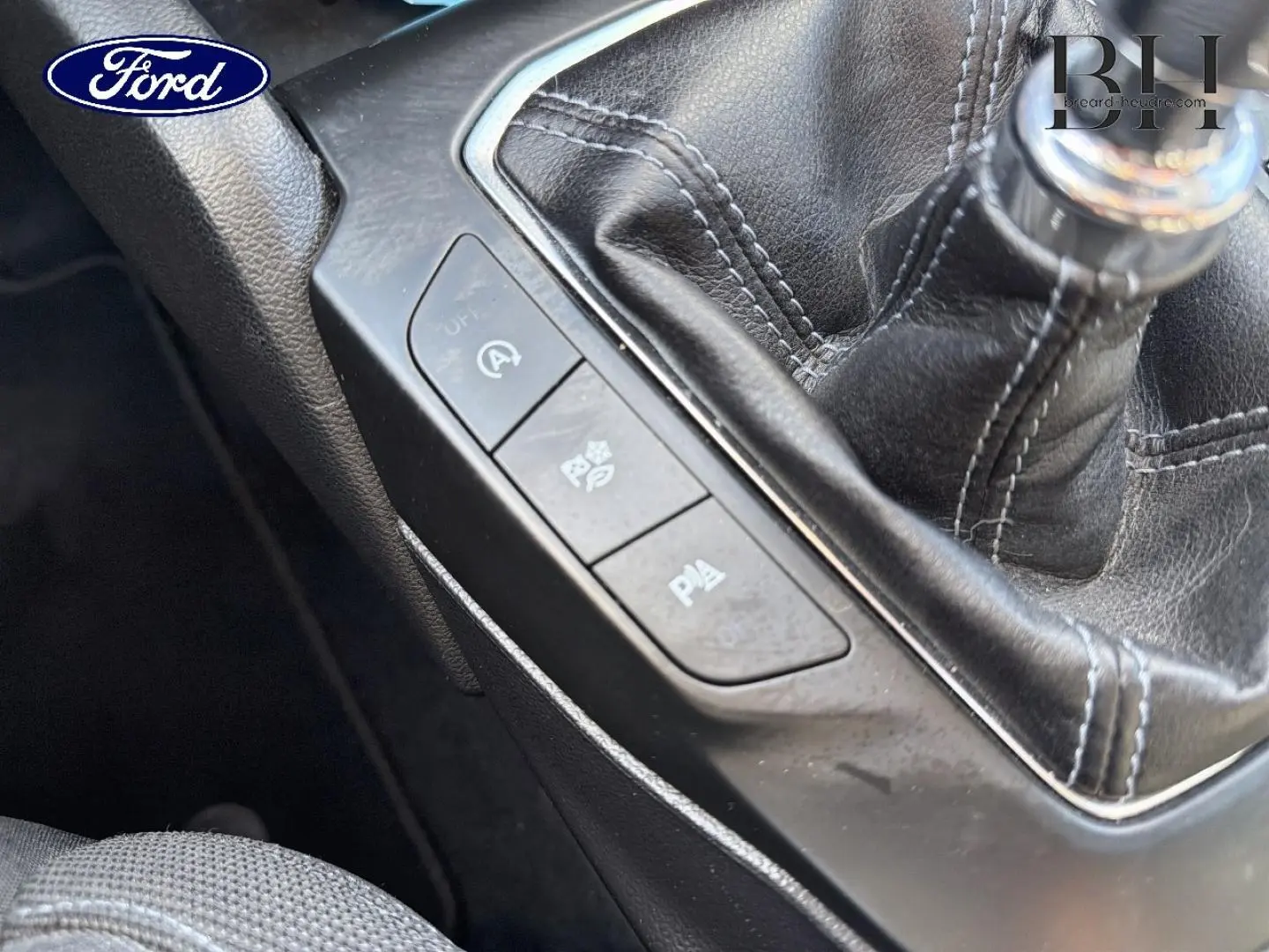 Gros plan sur la console centrale de la Ford Focus 2022 avec levier de vitesse manuel et boutons de contrôle noirs.