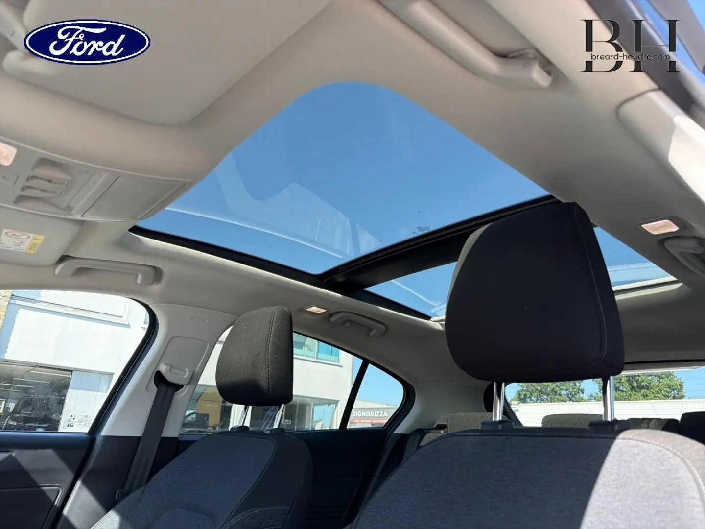 Vue intérieure de la Ford Focus 2022 avec toit panoramique ouvrant et sièges tissu noir côté gauche.