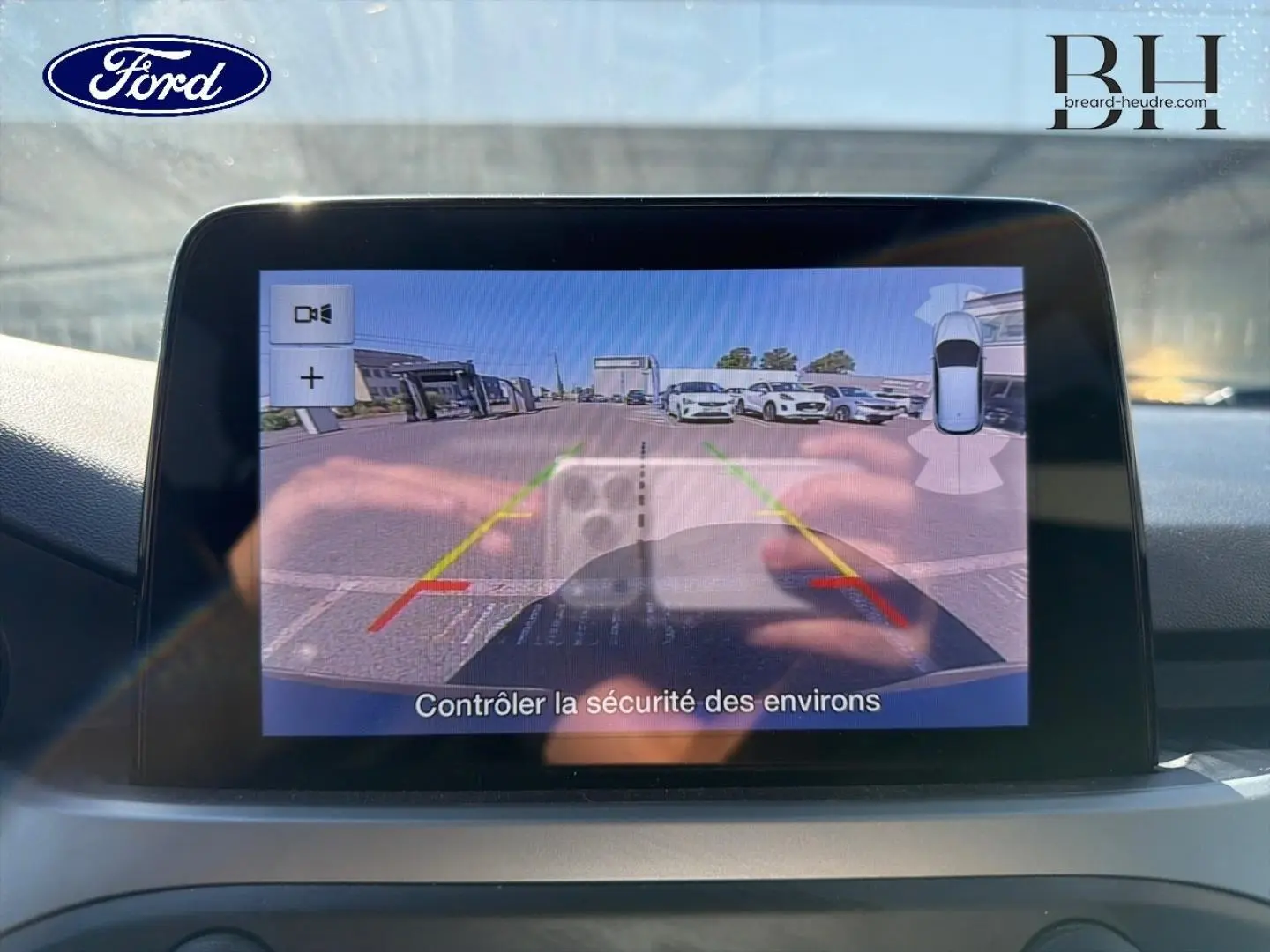 Écran tactile de la caméra de recul de la Ford Focus bleu azur, vue intérieure du tableau de bord en lumière naturelle.