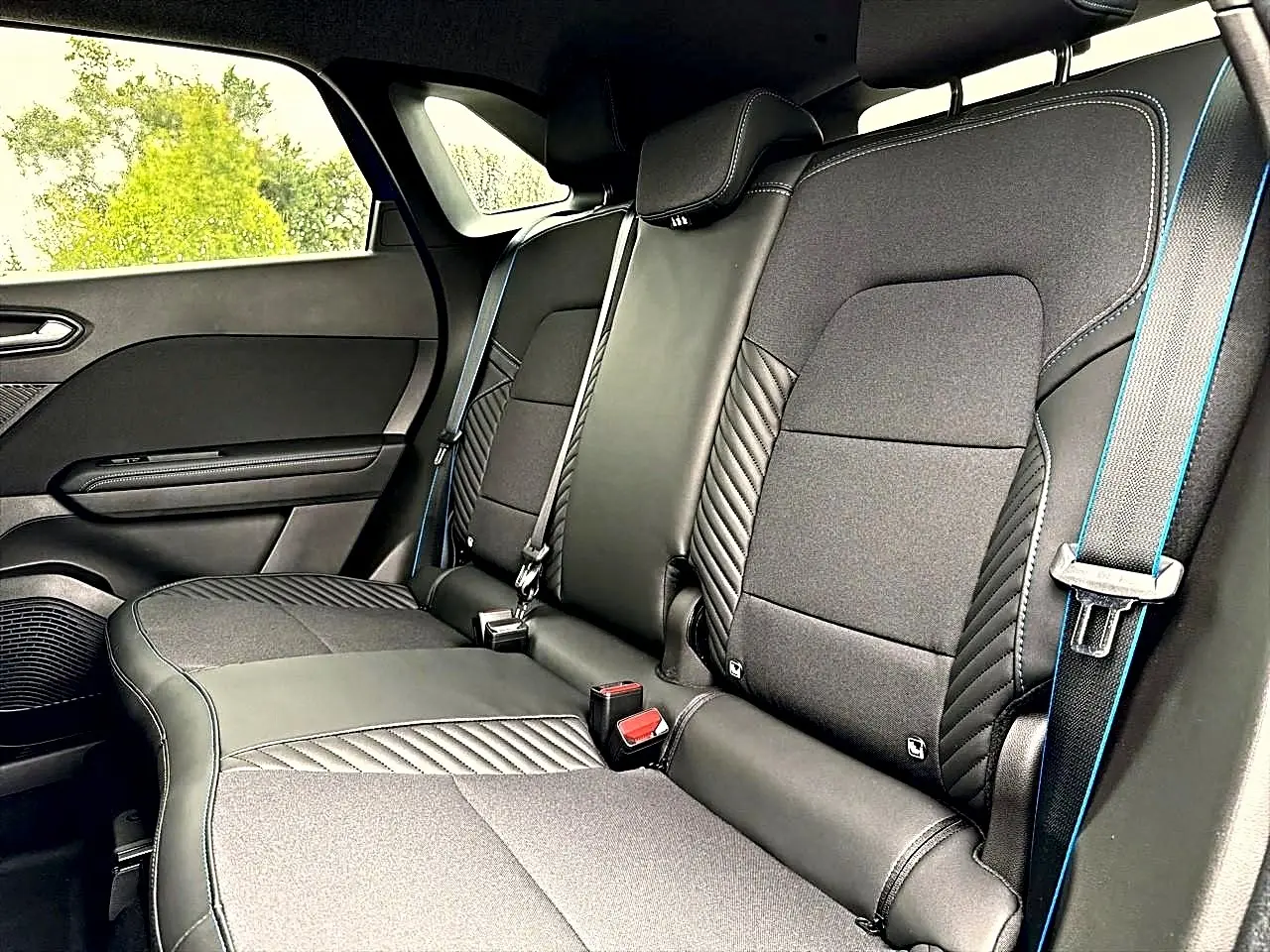 Vue intérieure côté droit des sièges arrière noirs avec surpiqûres bleues du Renault Symbioz 2026 hybride.