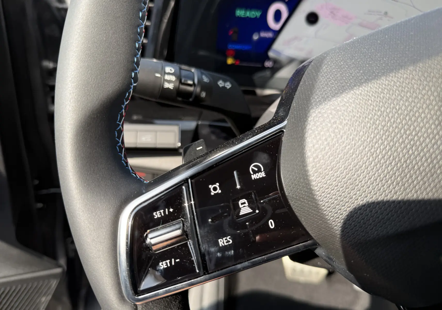 Gros plan sur les commandes du volant du Renault Espace gris schiste, mettant en valeur les boutons de régulateur et mode de conduite.