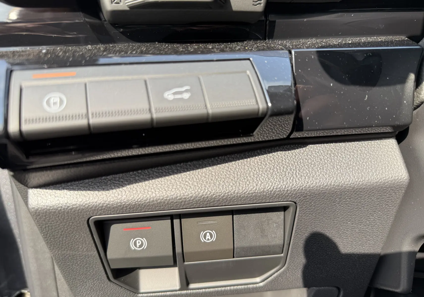 Gros plan sur les commandes de frein à main et ouverture du coffre du tableau de bord du Renault Espace gris 2025.