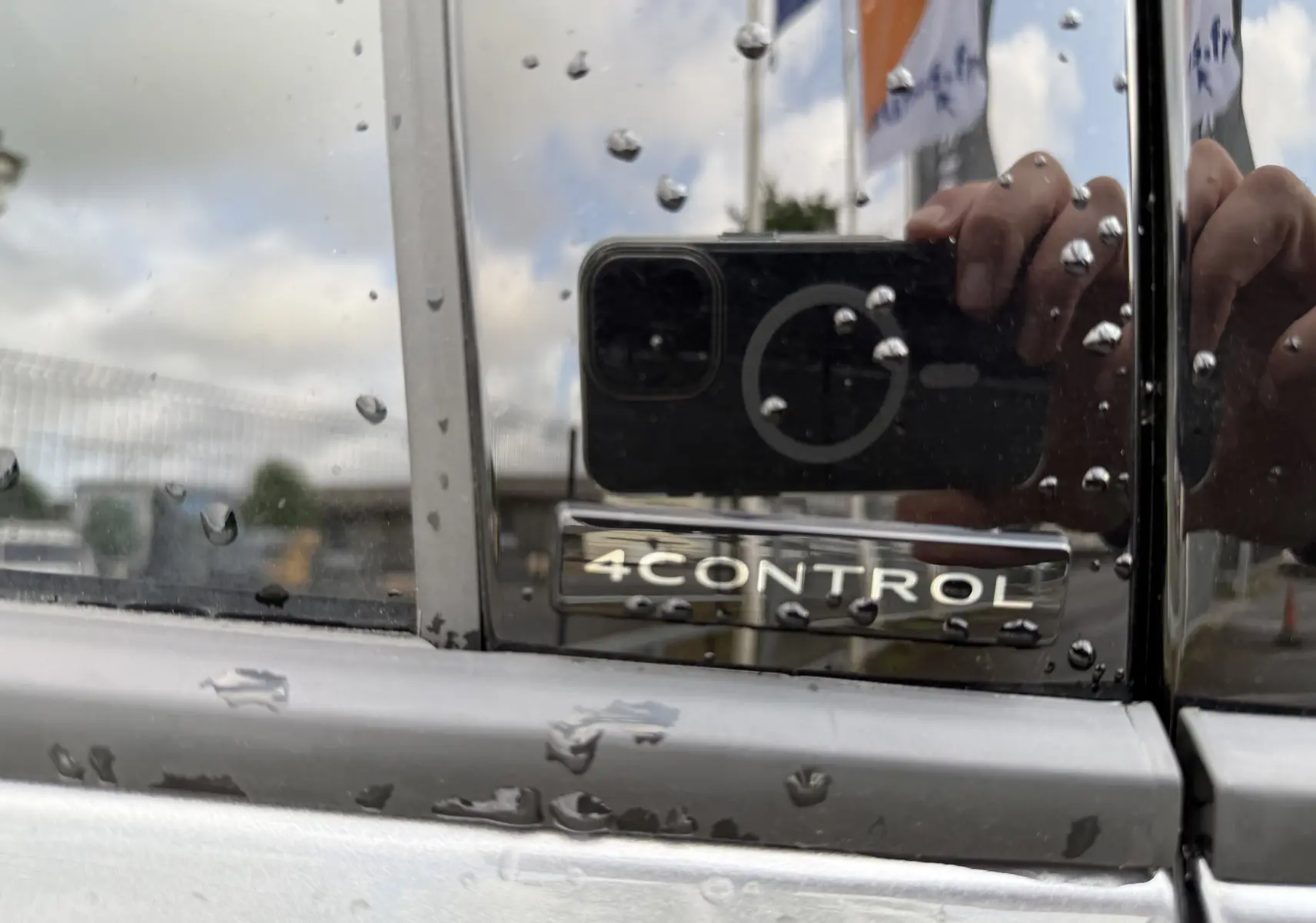 Gros plan sur l’inscription 4CONTROL sur la porte gris schiste métal d’un Renault Espace 2025, avec gouttes de pluie visibles.