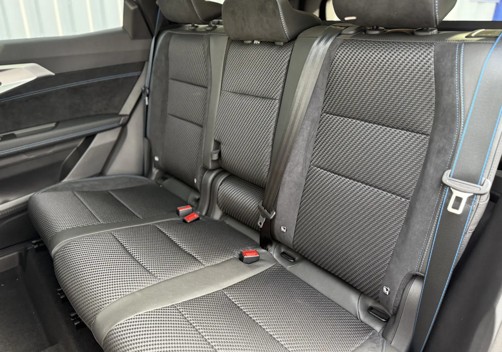 Vue latérale intérieure des sièges arrière noirs avec surpiqûres bleues du Renault Espace 2025 finition Esprit Alpine 7 places.