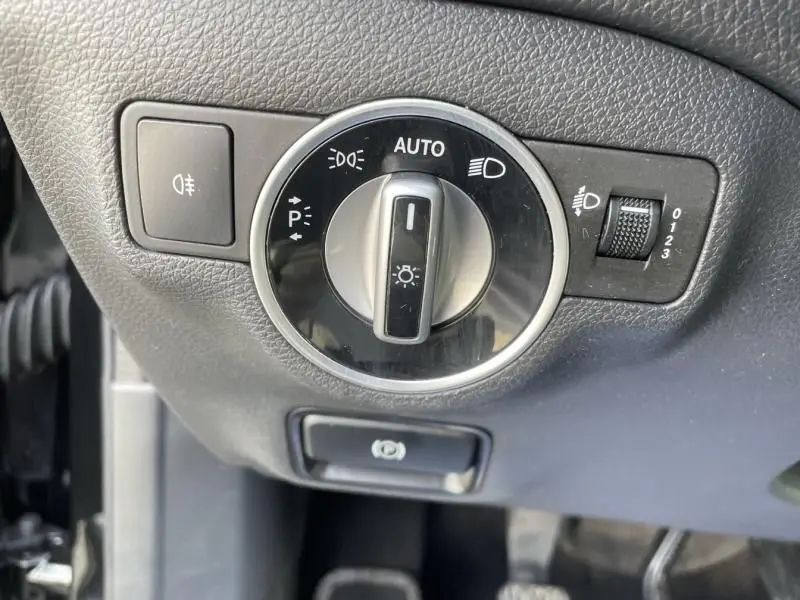 Gros plan sur le bouton de commande des phares d'un Mercedes GLA 200 D Sensation noir 2017, intérieur côté gauche.