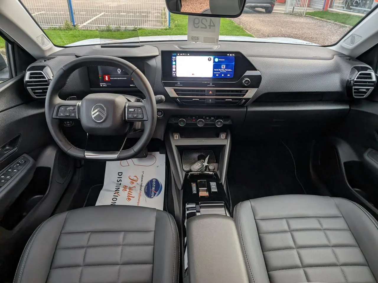 Intérieur noir de la Citroën C4 2025 vu de face, avec volant cuir, écran tactile et sièges matelassés.