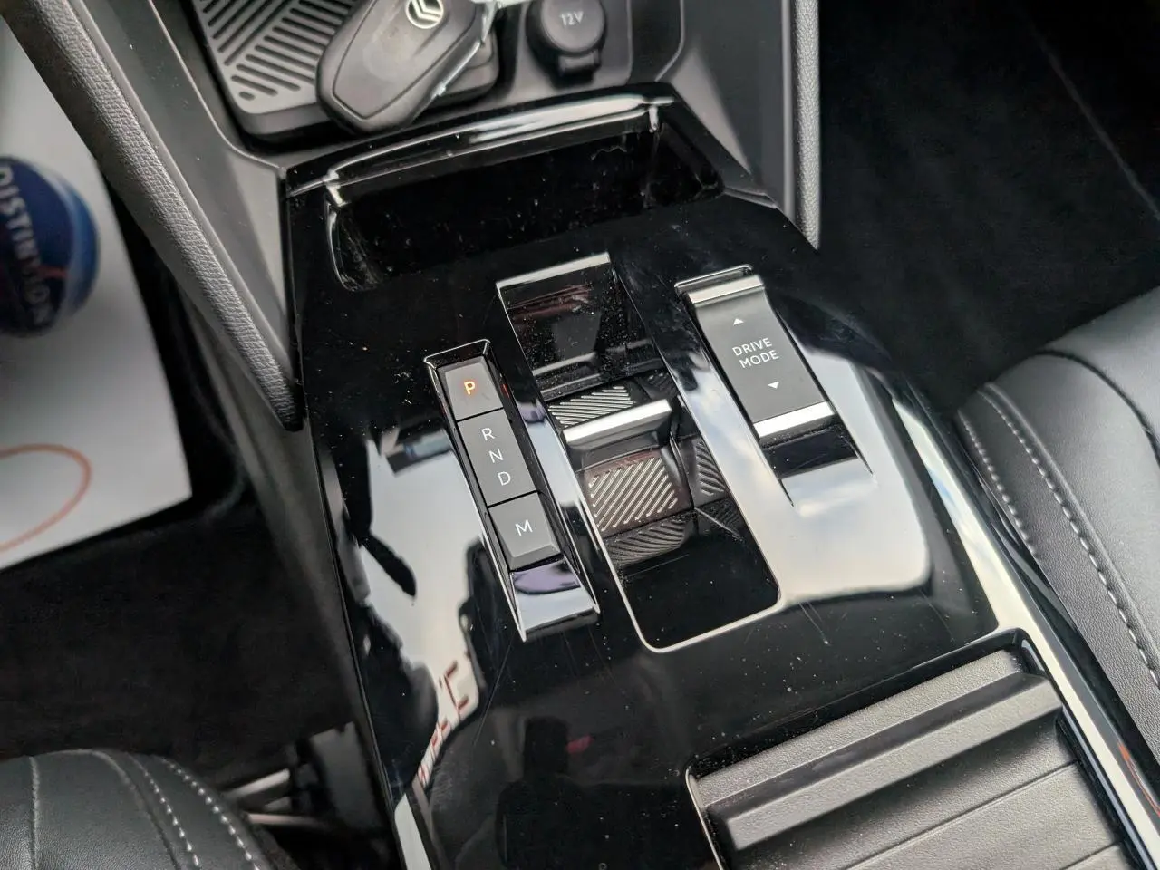 Gros plan sur la console centrale noire brillante de la Citroën C4 2025, avec commandes de boîte auto et mode de conduite.