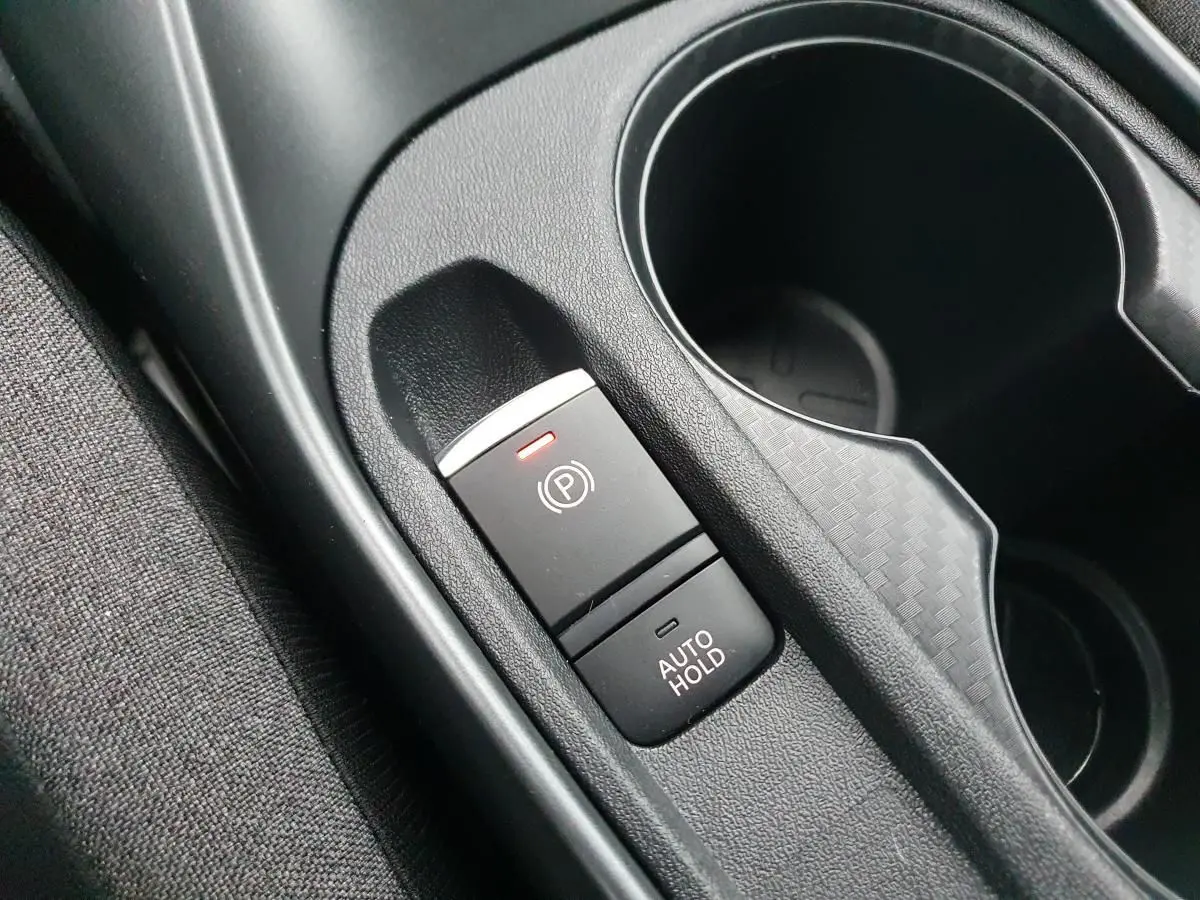 Gros plan sur le frein à main électrique et porte-gobelets noirs dans l'habitacle du Nissan Juke 2025.