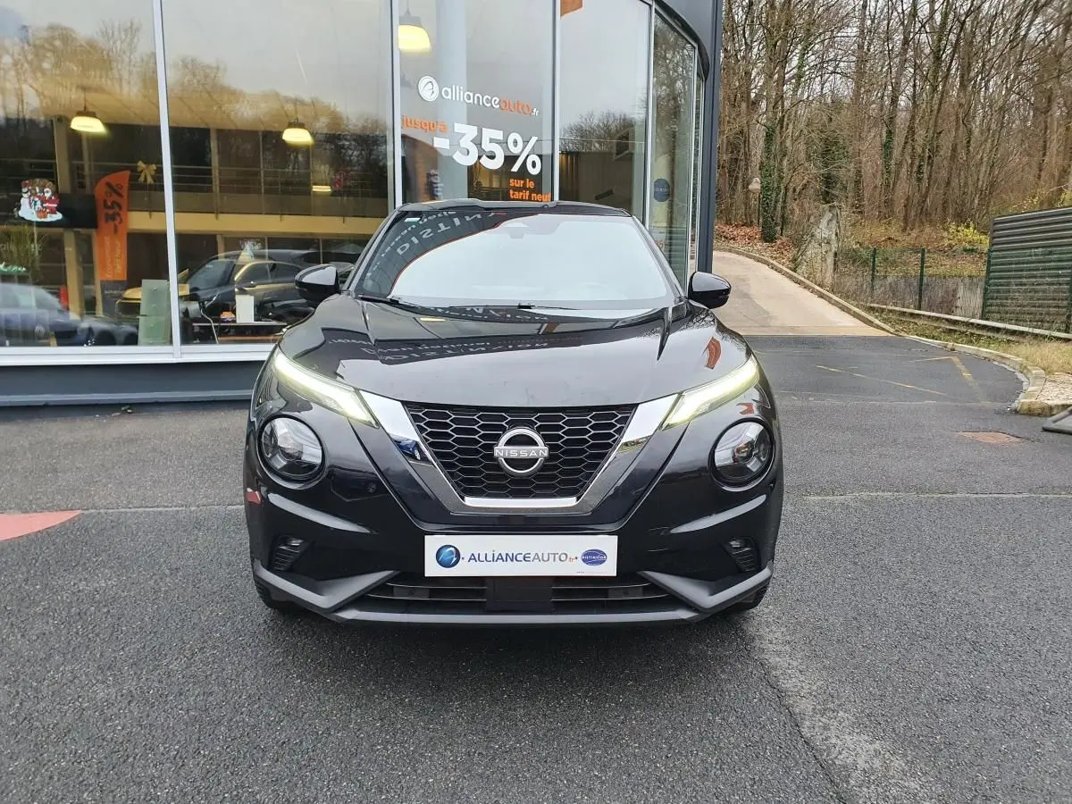 Vue avant d'un Nissan Juke noir 2025 avec phares LED allumés et calandre en V chromée.