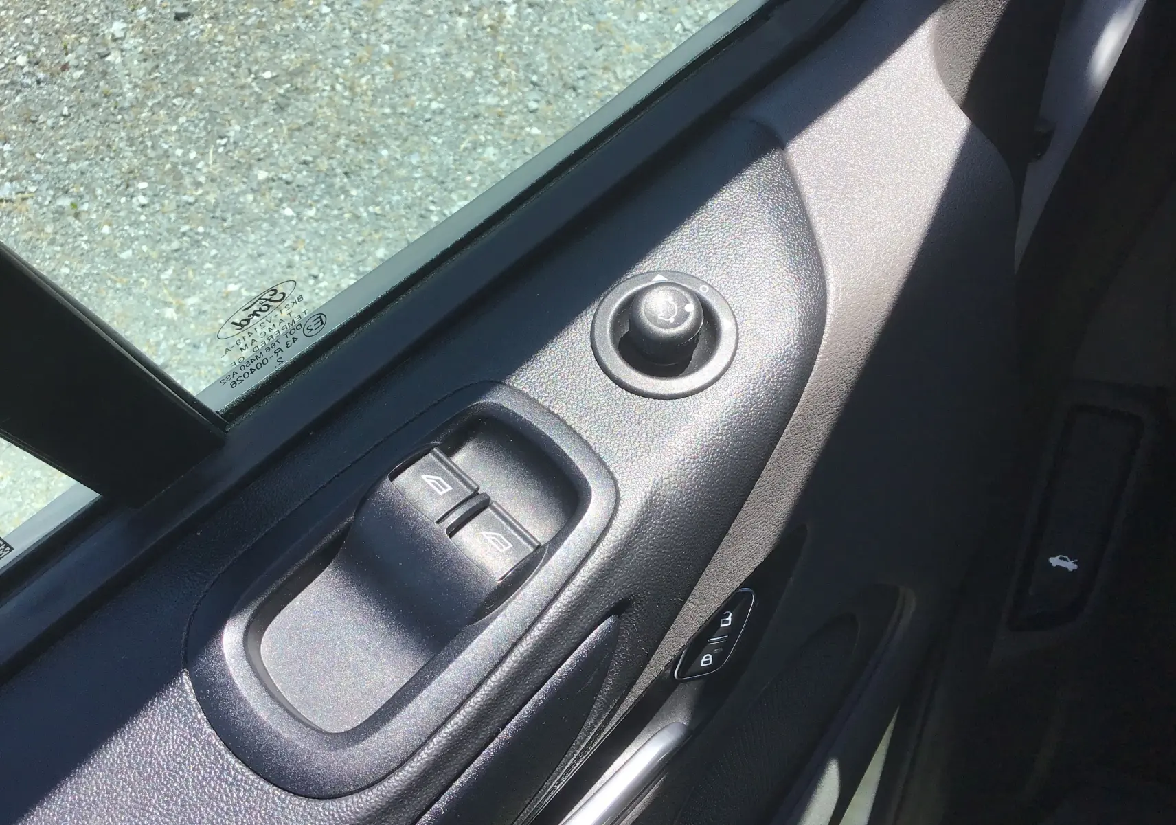 Vue rapprochée des commandes électriques de vitres et rétroviseurs sur la porte côté gauche d’un Ford Transit Custom blanc.