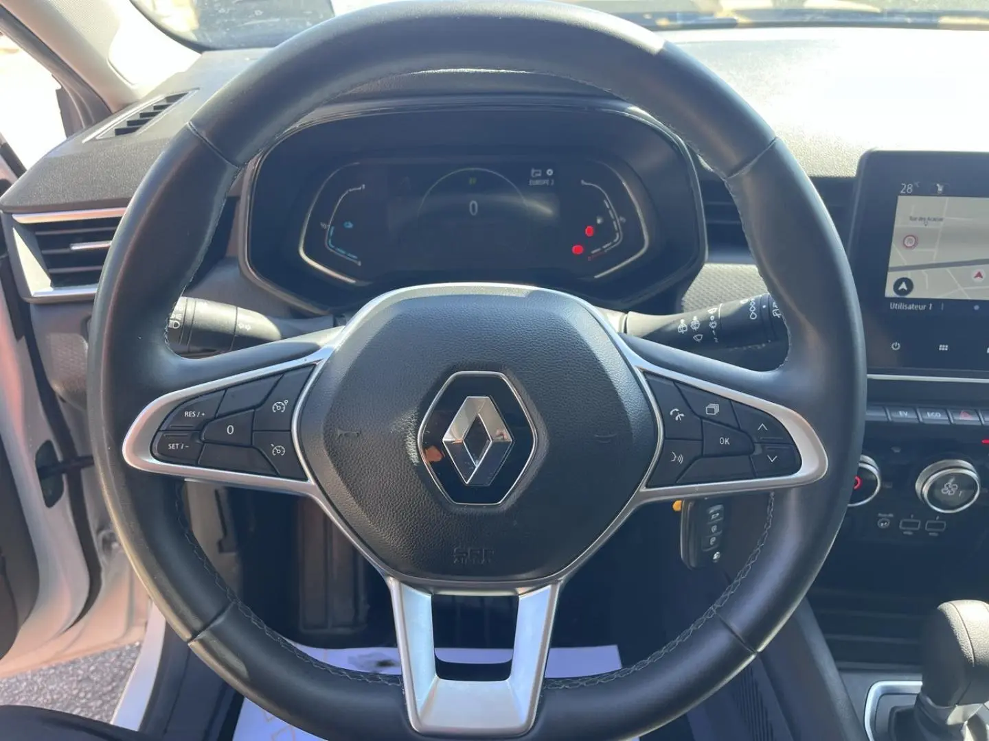 Vue intérieure centrée sur le volant noir de la Renault Clio 1.6 E-Tech 2021 avec tableau de bord digital et écran tactile.
