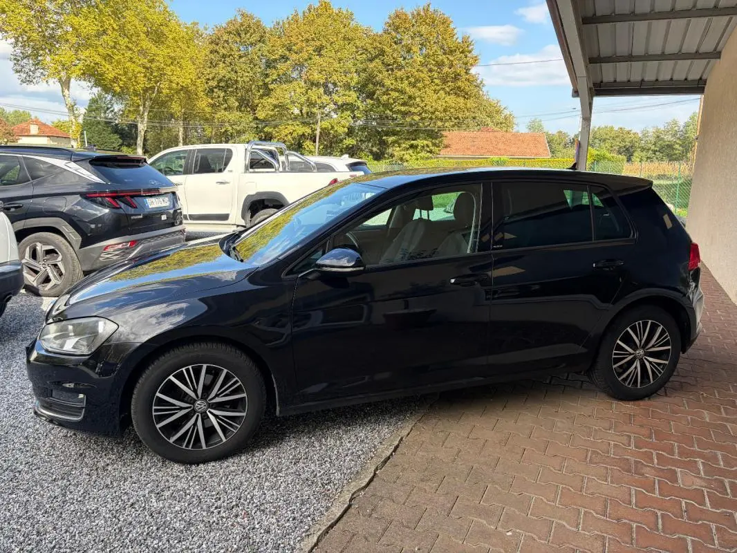 Volkswagen Golf 7 noire vue de profil côté gauche, stationnée sous abri avec jantes alliage distinctives.