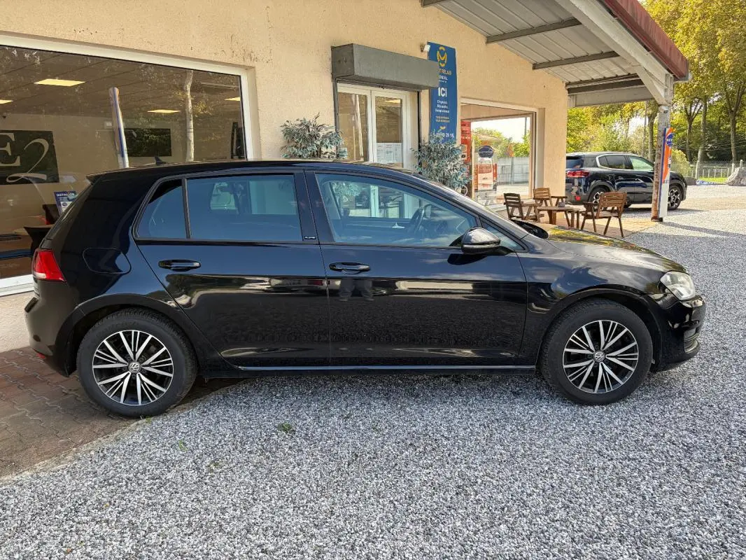 Volkswagen Golf 7 noire vue de profil côté gauche, avec jantes alliage et rétroviseurs électriques rabattables.