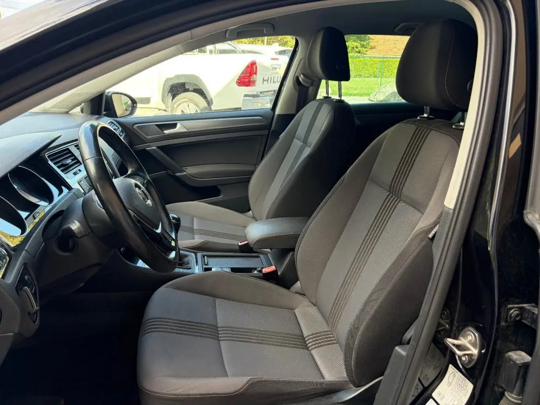 Intérieur de la Volkswagen Golf 7 noir, vue côté conducteur montrant sièges tissu et volant cuir multifonctions.