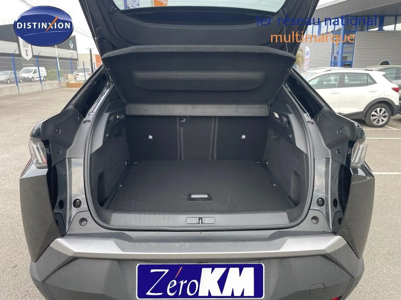 Coffre ouvert d'un Peugeot 3008 Hybrid noir perle métal vu de l'arrière, montrant un espace de chargement spacieux et propre.