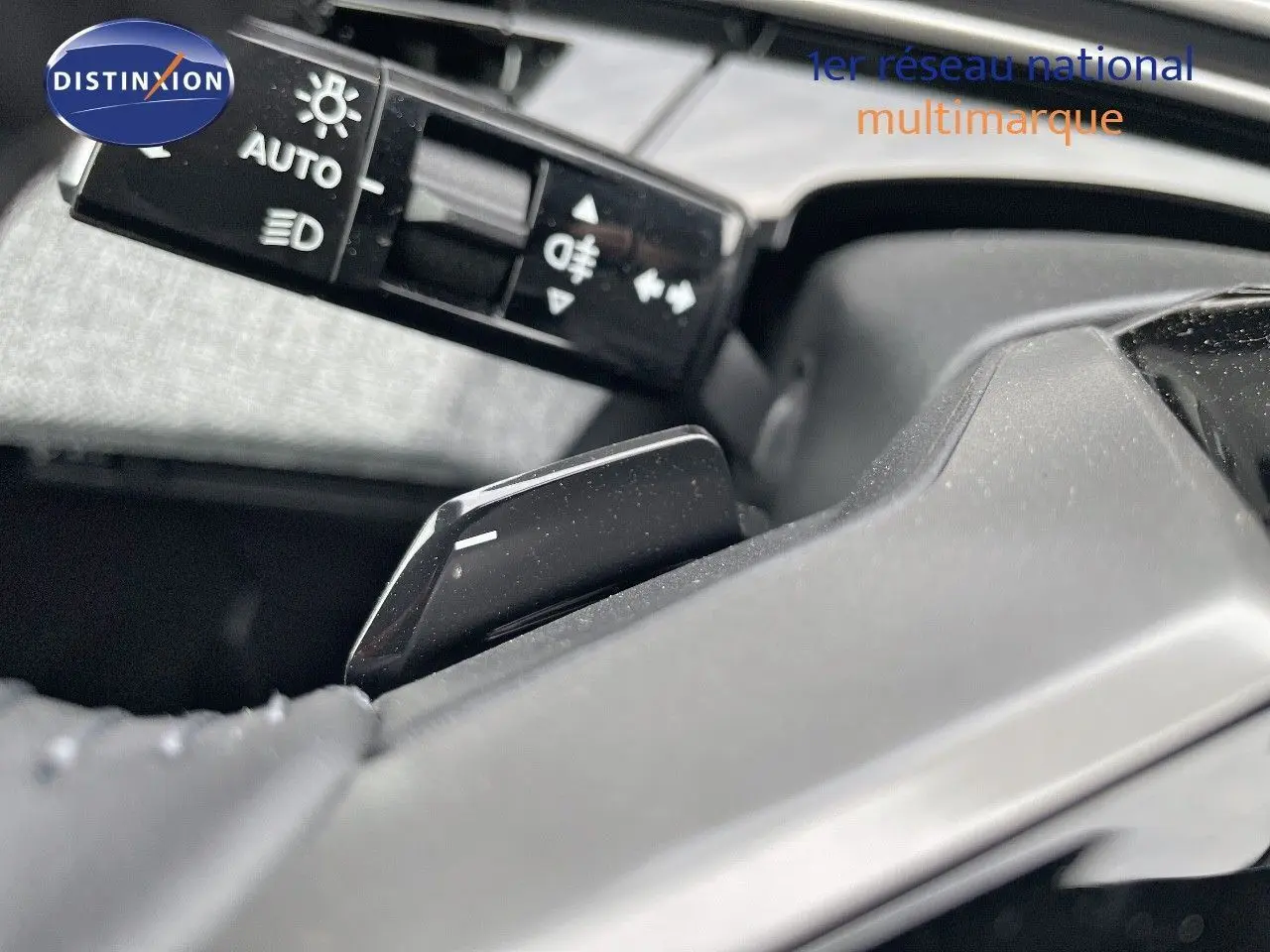 Gros plan sur la commande de feux et le levier de vitesses au volant d'un Peugeot 3008 noir perle métal 2025 hybride.