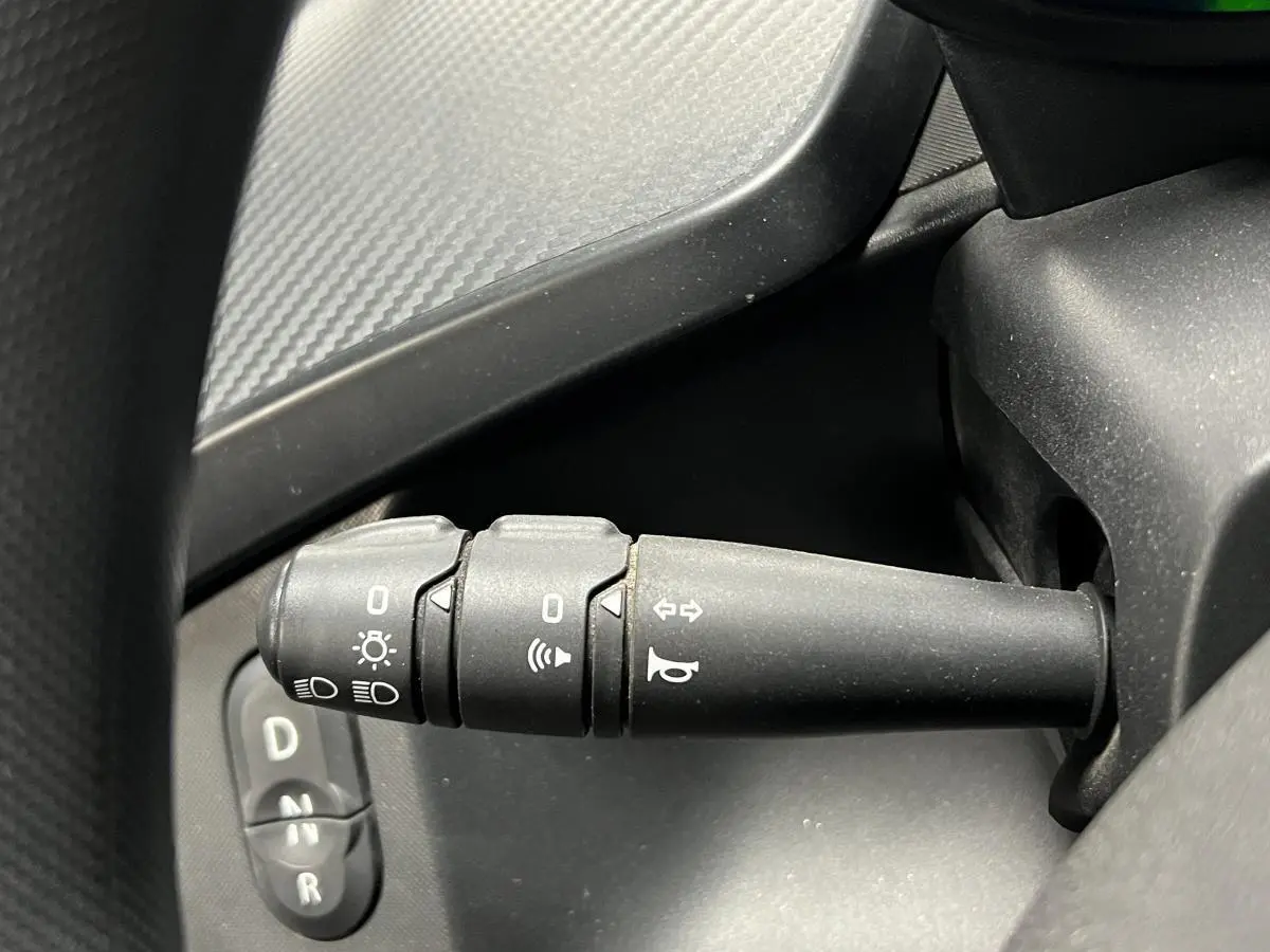 Gros plan sur la manette de clignotants noire côté gauche du tableau de bord d'une Renault Twizy orange.