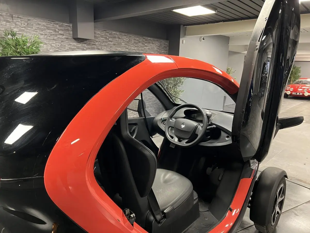 Vue intérieure côté droit de la Renault Twizy Intens 2019 orange avec porte élytre ouverte et siège noir visible.