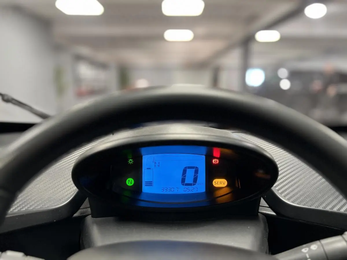 Vue rapprochée du tableau de bord numérique bleu de la Renault Twizy Intens orange, affichant vitesse et niveau batterie.