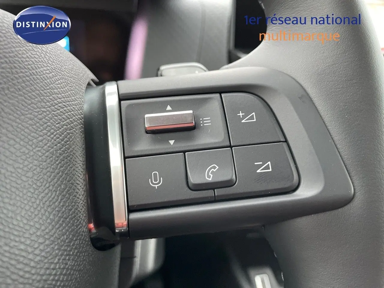 Gros plan sur les commandes multifonctions du volant noir d'une Citroën C4 gris platinium 2024.