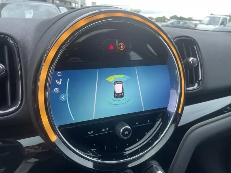 Affichage du système d'aide au stationnement sur l'écran circulaire avec éclairage orange intérieur d'une MINI Countryman gris 2021.