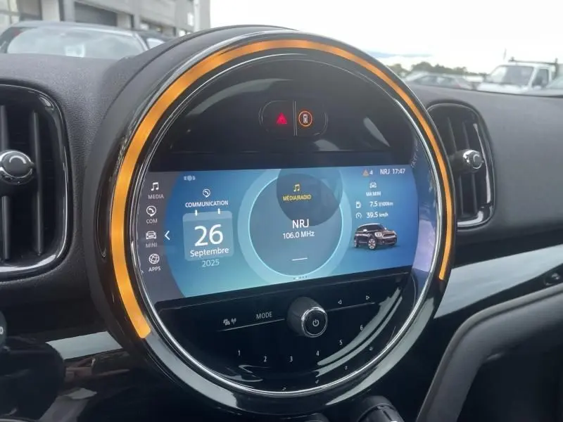 Tableau de bord circulaire éclairé en orange de la MINI Countryman Cooper gris, affichant l'écran multimédia central.