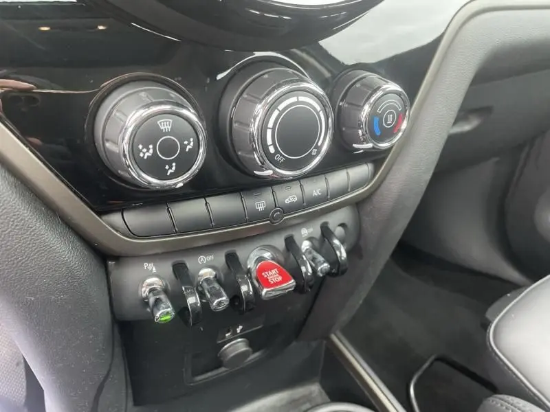 Gros plan sur la console centrale du MINI Countryman Cooper 136 gris 2021, avec commandes de climatisation et bouton start/stop rouge.