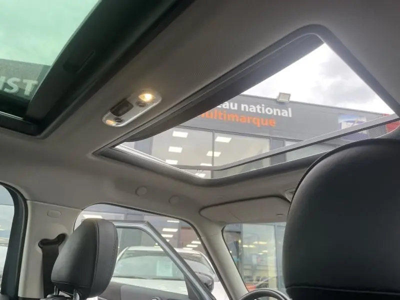 Toit ouvrant panoramique ouvert sur l'intérieur d'un MINI Countryman Cooper 136 gris, vue depuis les sièges arrière vers l'avant.