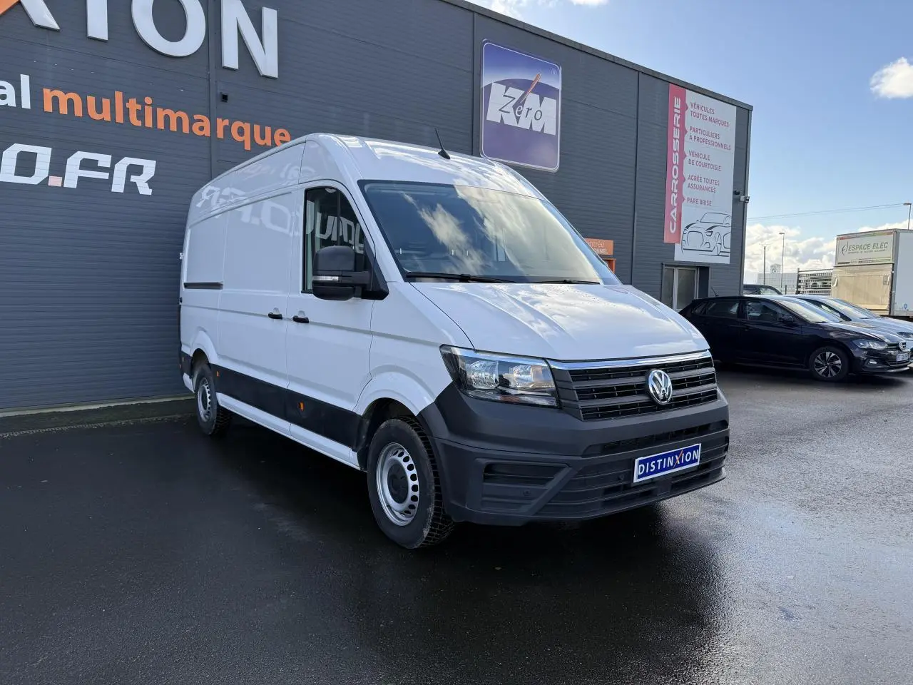 Volkswagen Crafter fourgon blanc vu en 3/4 avant droit, avec pare-chocs noir et porte coulissante à droite visible.