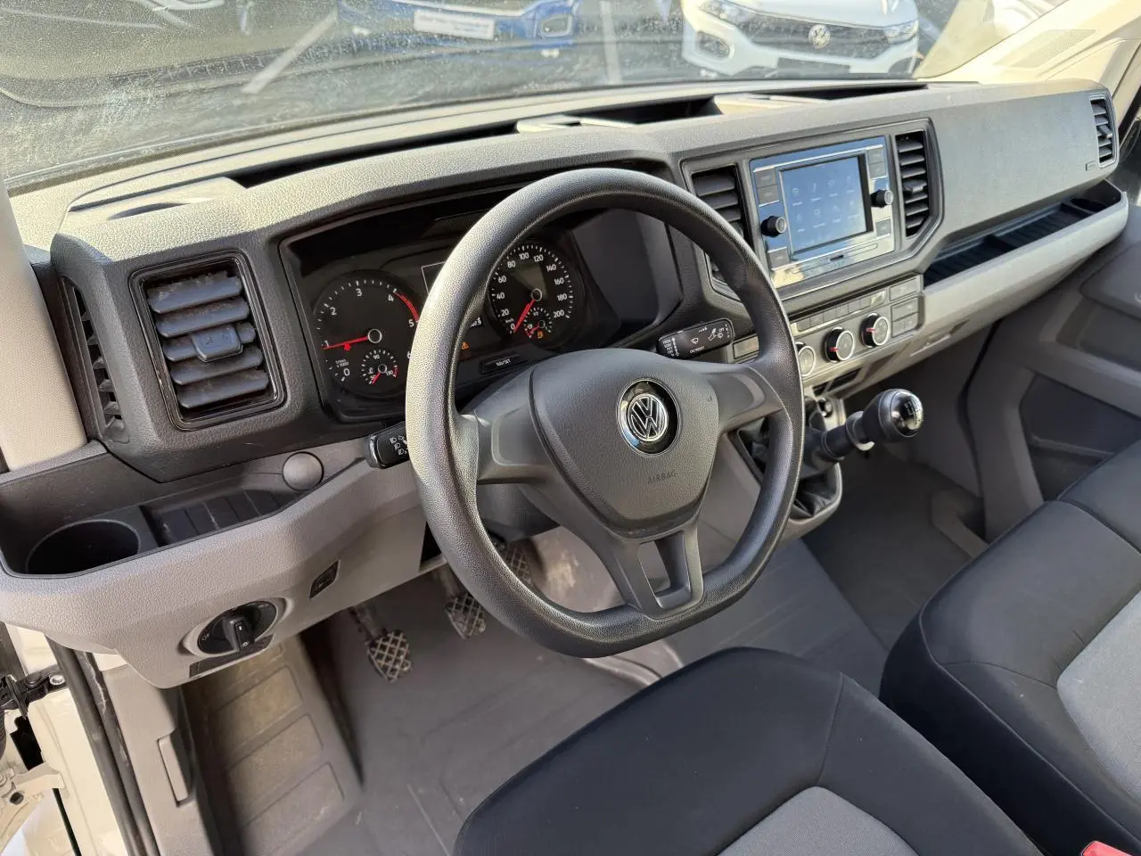 Vue intérieure du tableau de bord et volant multifonctions noir du Volkswagen Crafter Fourgon blanc 2023 avec boîte manuelle.