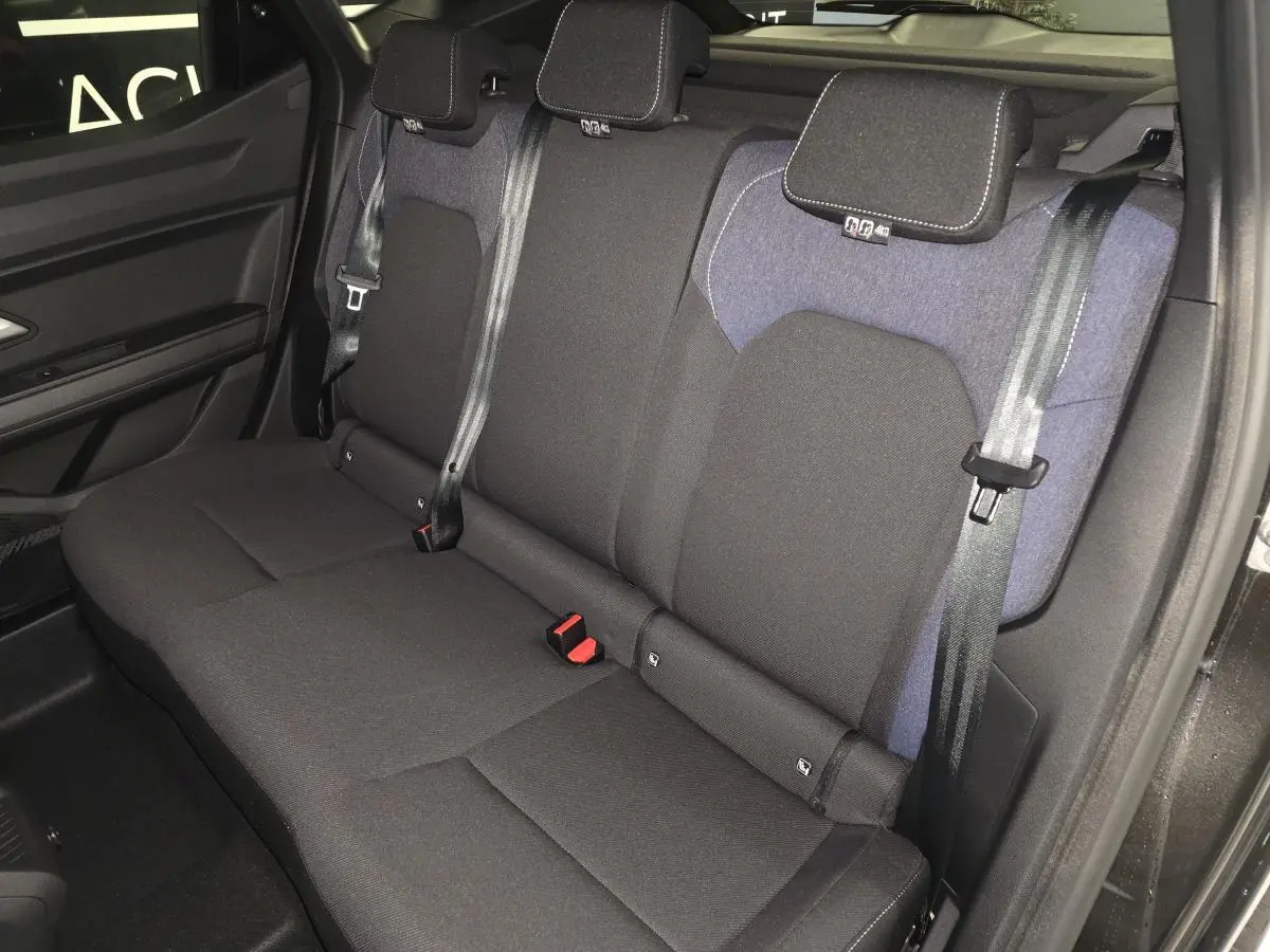Vue latérale de la banquette arrière noire et denim bleu du Dacia Duster 1.6 Hybrid 2025 avec ceintures trois points.