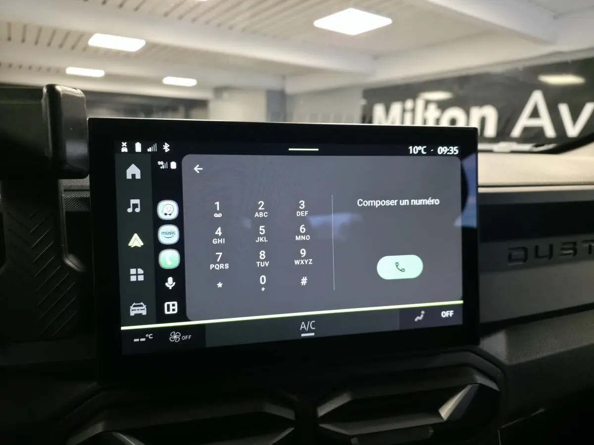 Écran tactile central affichant le clavier téléphonique, tableau de bord noir avec logo Duster en relief.