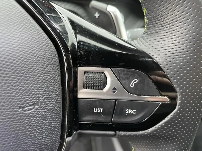 Gros plan sur les commandes au volant côté gauche du Peugeot 2008 GT-LINE rouge métal, avec molette et boutons fonctionnels.