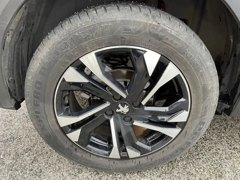 Gros plan sur la jante noire et argentée du Peugeot 2008 130 GT-LINE EAT8 rouge métal de 2022, avec logo lion central.