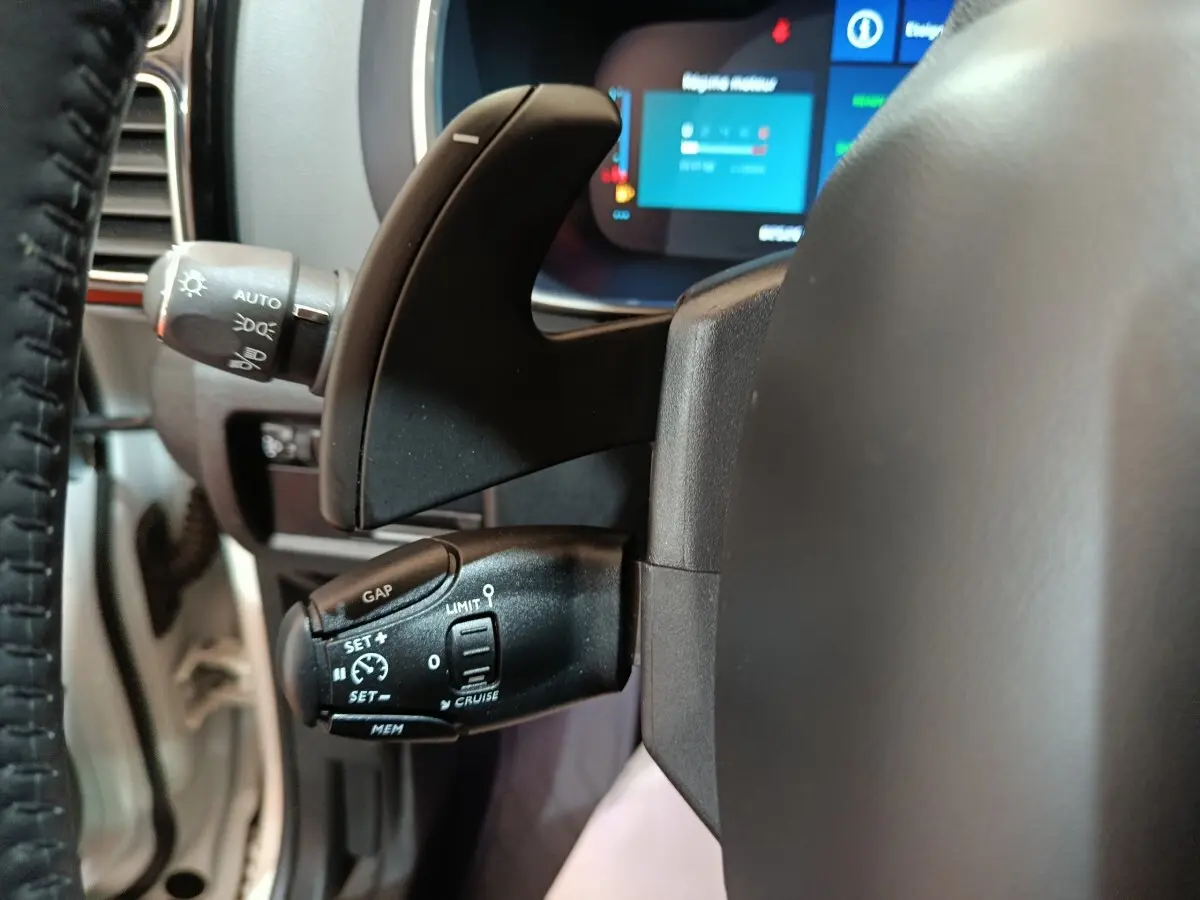 Gros plan sur la commande de régulateur de vitesse et palettes au volant d’un Citroën C5 Aircross blanc hybride rechargeable.