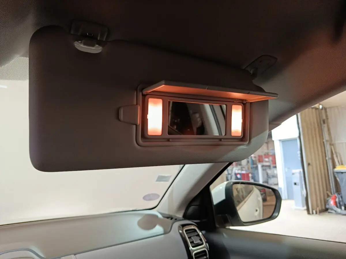 Miroir de courtoisie éclairé sur pare-soleil côté conducteur dans l’habitacle d’un Citroën C5 Aircross blanc.