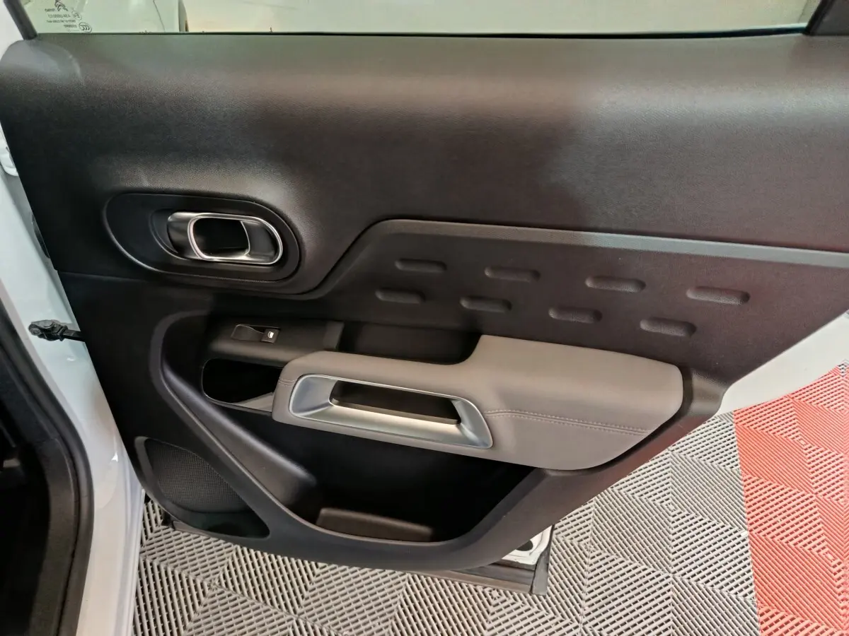Vue intérieure côté gauche de la porte avant d’un Citroën C5 Aircross Hybrid blanc avec poignée argentée et accoudoir gris.