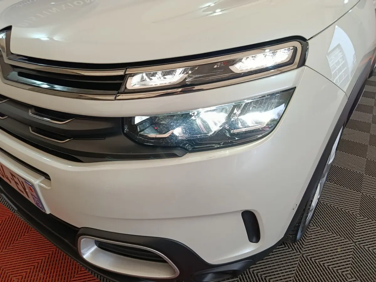 Gros plan sur l'avant droit blanc du Citroën C5 Aircross Hybrid avec ses phares LED allumés et calandre chromée.