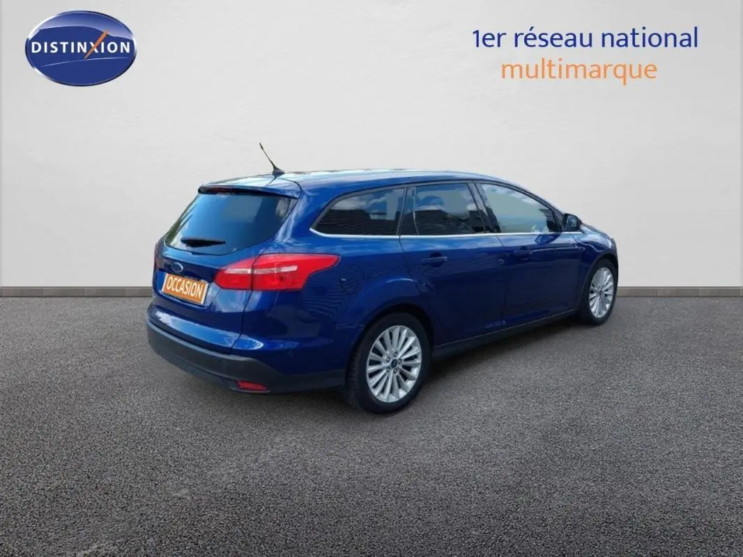 Ford Focus SW bleu foncé vue 3/4 arrière droit, vitres surteintées et jantes alliage 17 pouces visibles.